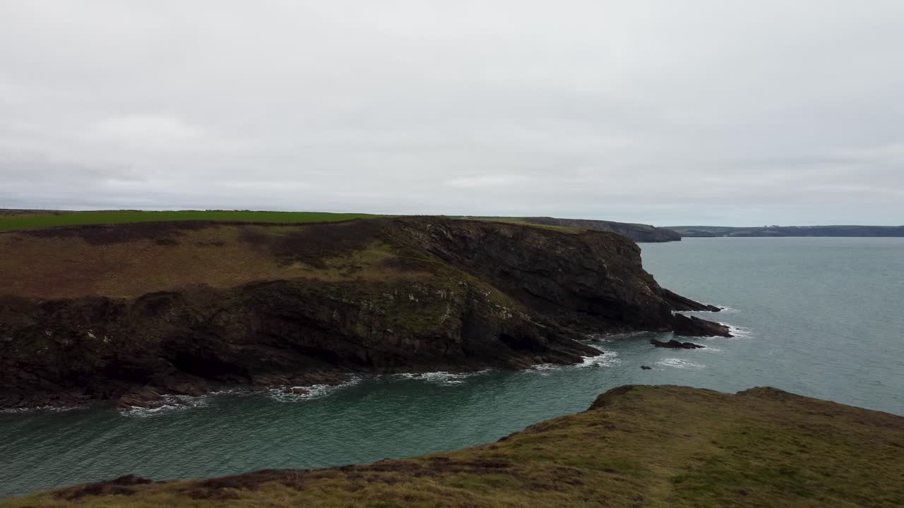 disparo de drones aéreos en lo alto del acantilado en retirada con olas marinas y espectacular costa rocosa de pembrokeshire reino unido 4k