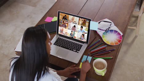 Caucasian-female-teacher-using-laptop-on-video-call-with-students,-making-notes