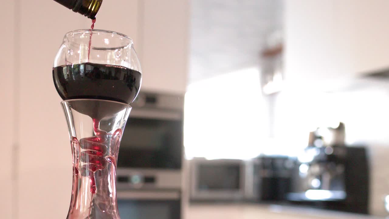 Vino tinto vertiéndose de una botella a través de un aireador de cristal en un decantador en interiores