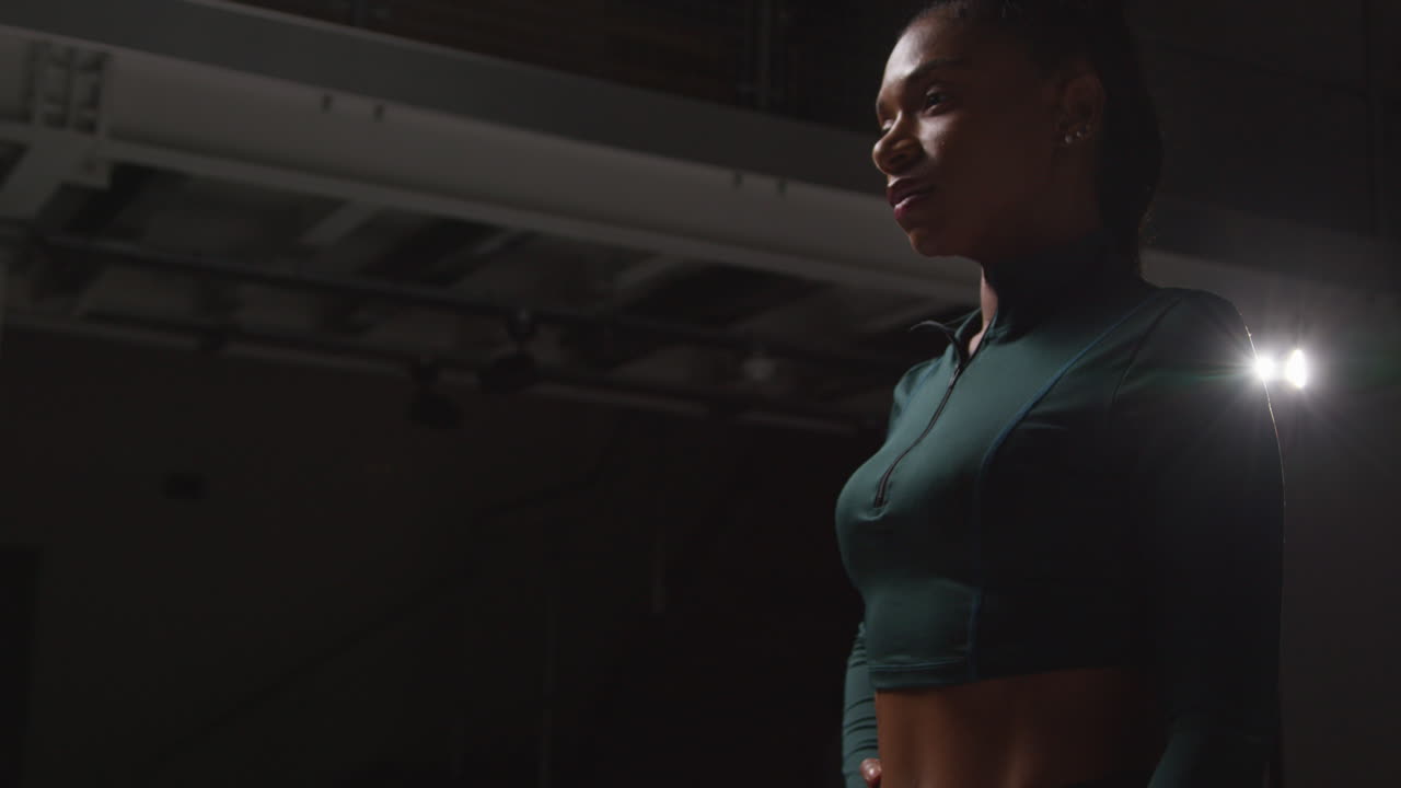 Serious Female Athlete Wearing Tracksuit Training And Preparing Psychologically For Sports Event In Gym With Low Key Lighting 1