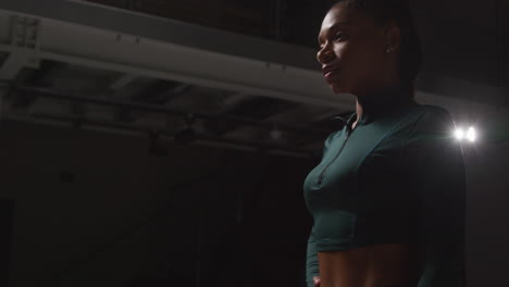 serious female athlete wearing tracksuit training and preparing psychologically for sports event in gym with low key lighting 1