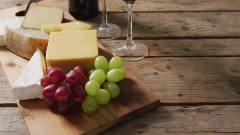 video de quesos y uvas a bordo botella de vino y vasos en mesa de madera, con espacio para copiar