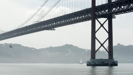 Distinctive-Lisbon-Suspended-Bridge-Over-Quiet-River-Under-Blue-Sky,-Portugal