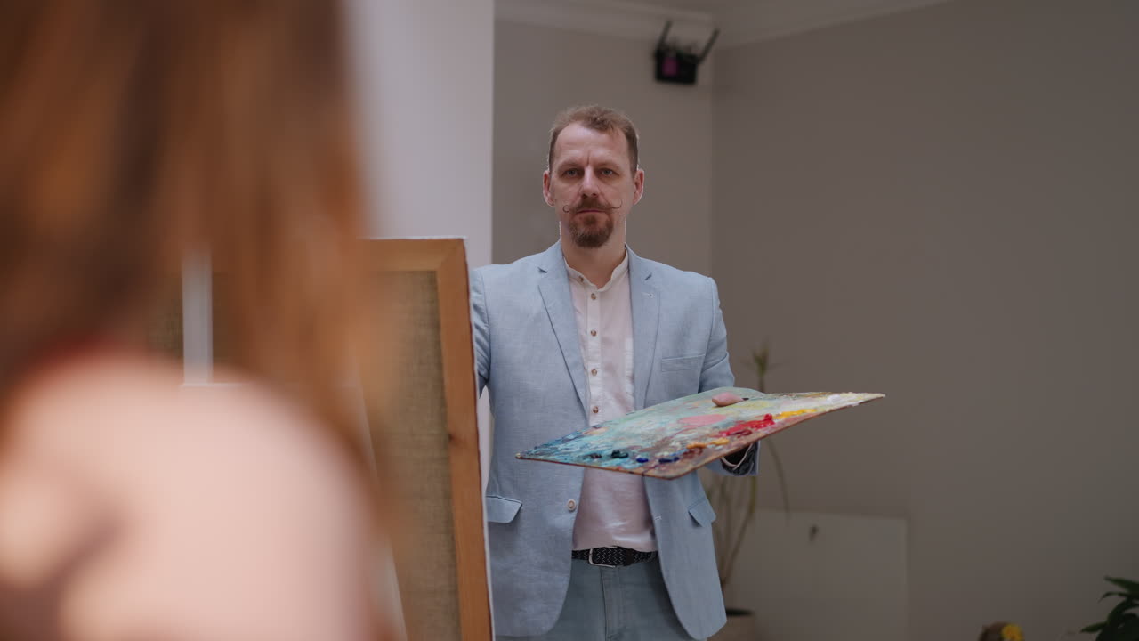 художник размышляет о модели в студии. зрелый художник с бородой изучает женщину, которая ищет особую перспективу в мастерской. портретистское вдохновение