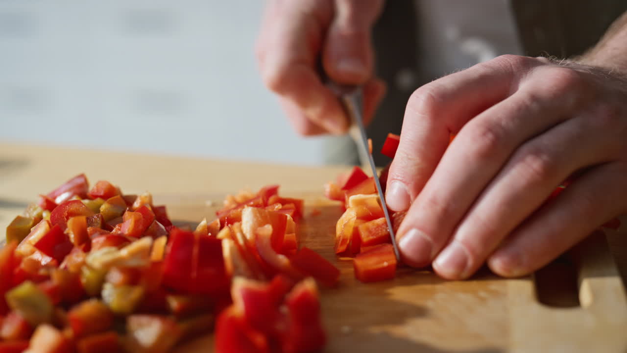 Chef hands slicing pepper on board kitchen closeup. Man chopping vegetables
