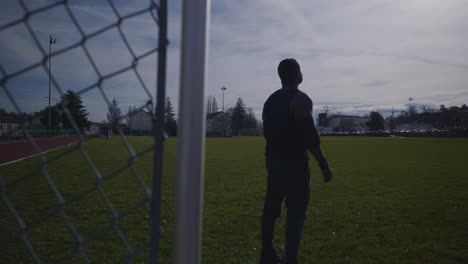 Mann-Geht-In-Der-Nähe-Eines-Metallzauns-Und-Beginnt-Zu-Beten---Starker-Athletischer,-Muskulöser-Schwarzer-Mann,-Fitnesstraining-Im-Freien,-Vorbereitung-In-4k