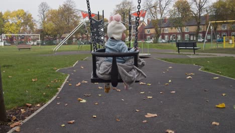 niña en columpio en un patio de juegos desolado debido a covid19, inglaterra