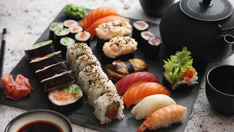 assortment of different kinds of sushi rolls placed on black stone board