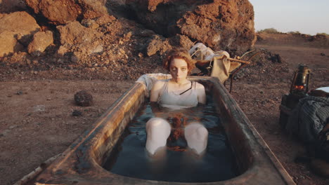 woman submerging in water in dirty bath in dystopian world