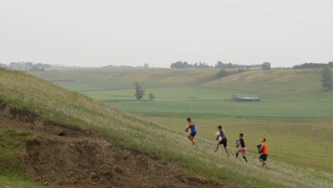 side view of fit mixed-race people carrying weights while climbing a hill at countryside 4k