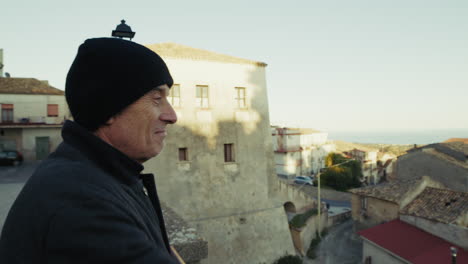 retired elderly man looks at the view of his small medieval village in calabria