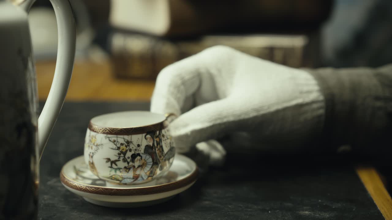 Antique expert inspects china porcelain tea-cup with magnifying glass