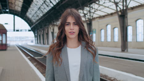 woman at a train station removing her face mask
