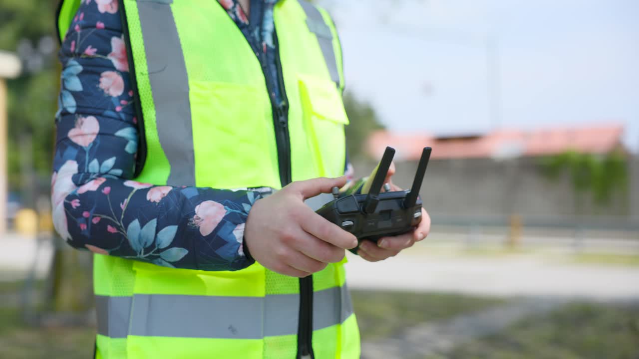 piloto de avión no tripulado mujer irreconocible con chaleco de alta visibilidad sostiene y utiliza el control remoto al aire libre en el parque