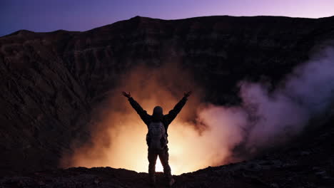 man with arms outstretched at sunrise in volcano crater