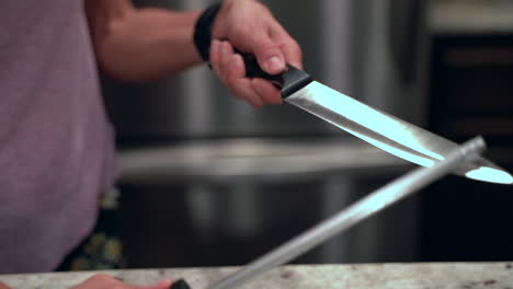 closeup of woman sharpening knife in slow motion with light bouncing off the blade