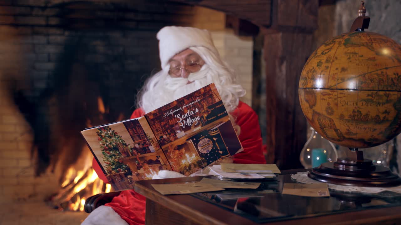 Santa reading magic book. Real Santa Claus looking into a Christmas book on the fireplace background. Round globe on the table. Christmas spirit concept.