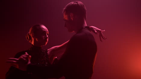 bailarines realizando bailes latinos con un fondo de luz roja. una pareja bailando en el salón de baile.