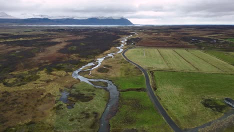 river by agricultural farmland in iceland countryside during summer, aerial