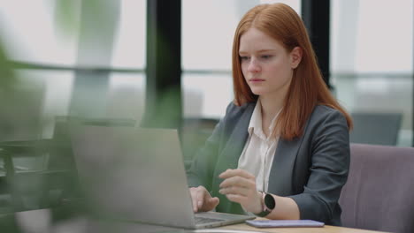 Una-Mujer-De-Negocios-Exitosa-Está-Trabajando-Con-Una-Computadora-Portátil-En-La-Oficina-Una-Bella-Dama-Con-Chaqueta-Gris-Leyendo-Un-Acuerdo