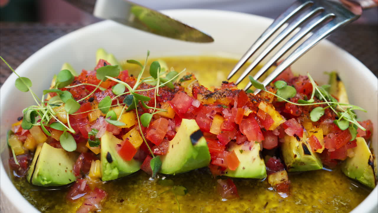 Close up of a woman eating avocado with cut up tomatoes