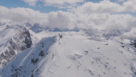 hikers traversing a snowy mountain ridge in a vast alpine landscape