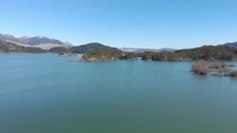 Fast-Aerial-over-artificial-Mountain-lake-sunny-winter-day