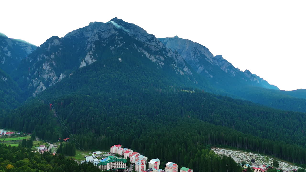 Residential area in the lush green pine tree woods. Spectacular mountains surround the area. Southern Carpathians, Romania