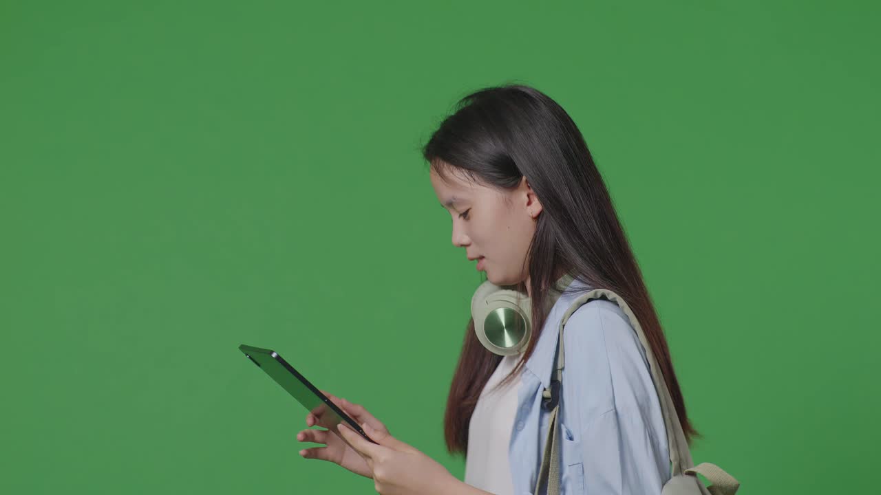 녹색 화면 배경 스튜디오에서 는 동안 태블릿을 사용하여 배을 가진 아시아 십대 소녀 학생