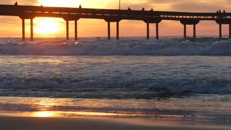 pier in sea water on beach. ocean waves, sky at sunset. california coast vibes.