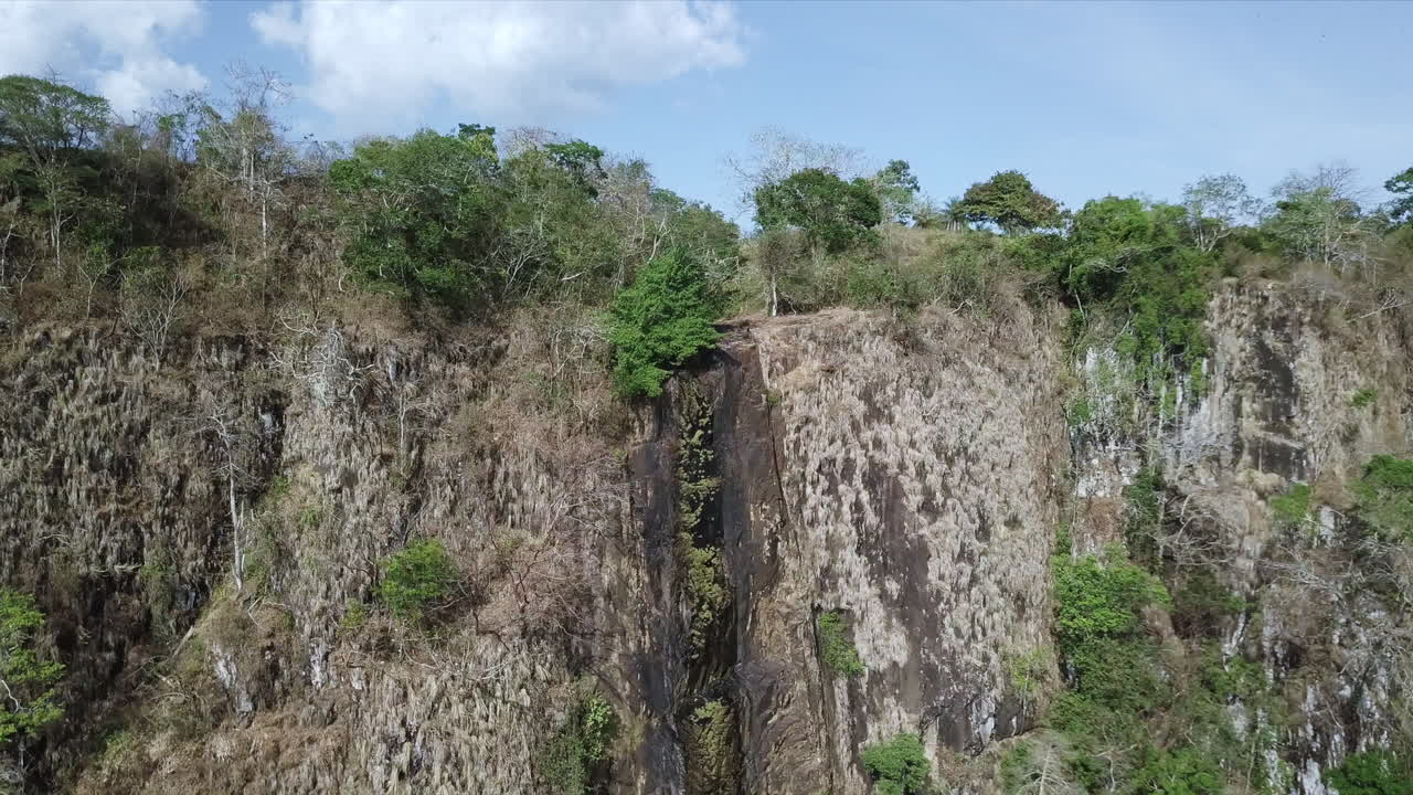 toma aérea volando hacia la cresta de una cascada seca en meseta de chorcha, buitres negros volando a través, chiriquí, panamá