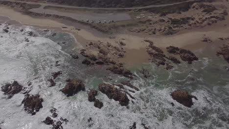 Long,-slow-aerial-focuses-on-dead-whale-carcass-washed-up-onto-beach