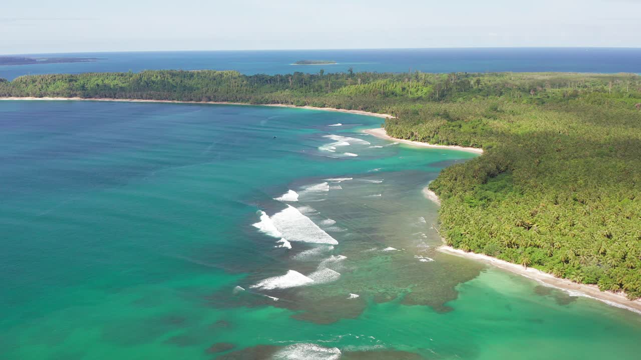 Aerial flight above breaking turquoise waves in majestic Indonesian lagoon