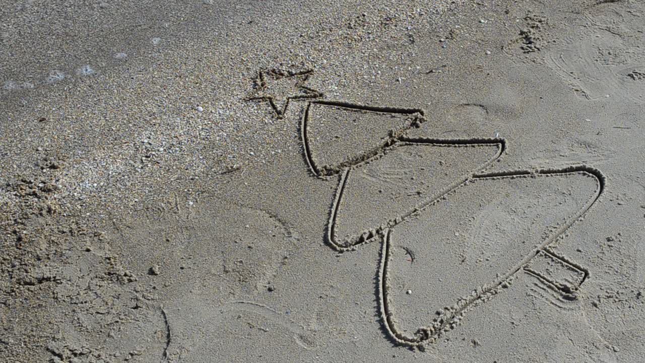 Fir-tree drawing on sand. Shooting on the beach