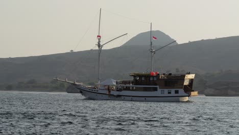 tourist boat cruises the sea against the backdrop of a mountain on komodo island