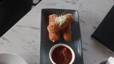 dish of croquettes on thin plate with its ketchu on the side, restaurant food