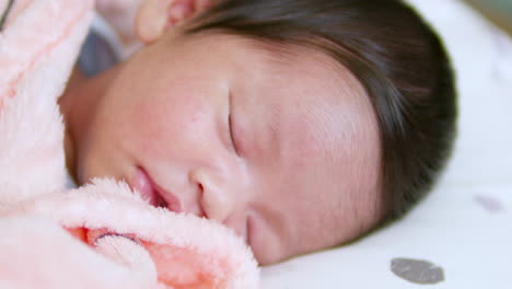 panning on a close-up shot of an adorable newborn baby sleeping peacefully on her crib as she is wrapped in her cottony blanket