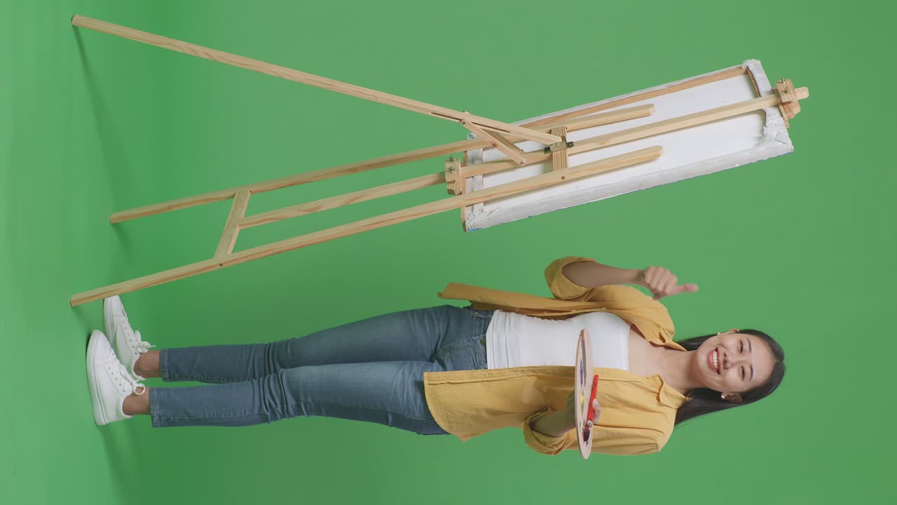 그림 기둥 앞에 엄지손가락을 들고 있는 예술가