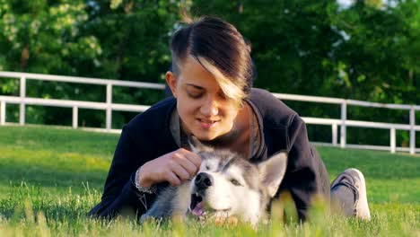 beautiful young woman playing with funny husky dog outdoors in park