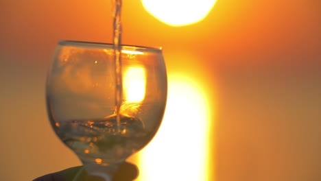 Bei-Sonnenuntergang-Wasser-In-Ein-Glas-Gießen