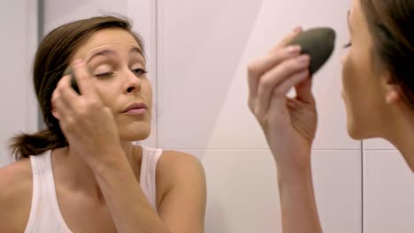 hermosa mujer haciendo el maquillaje en el baño