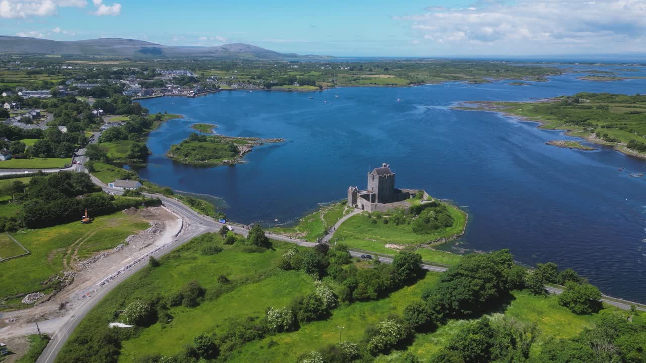 Reverse aerial dolly view from drone, overlooking the Medieval Dunguaire Castle, a 16th century castle built in the shore of Galway Bay in Kinvarra - Summer touristic Irish destination. Ireland