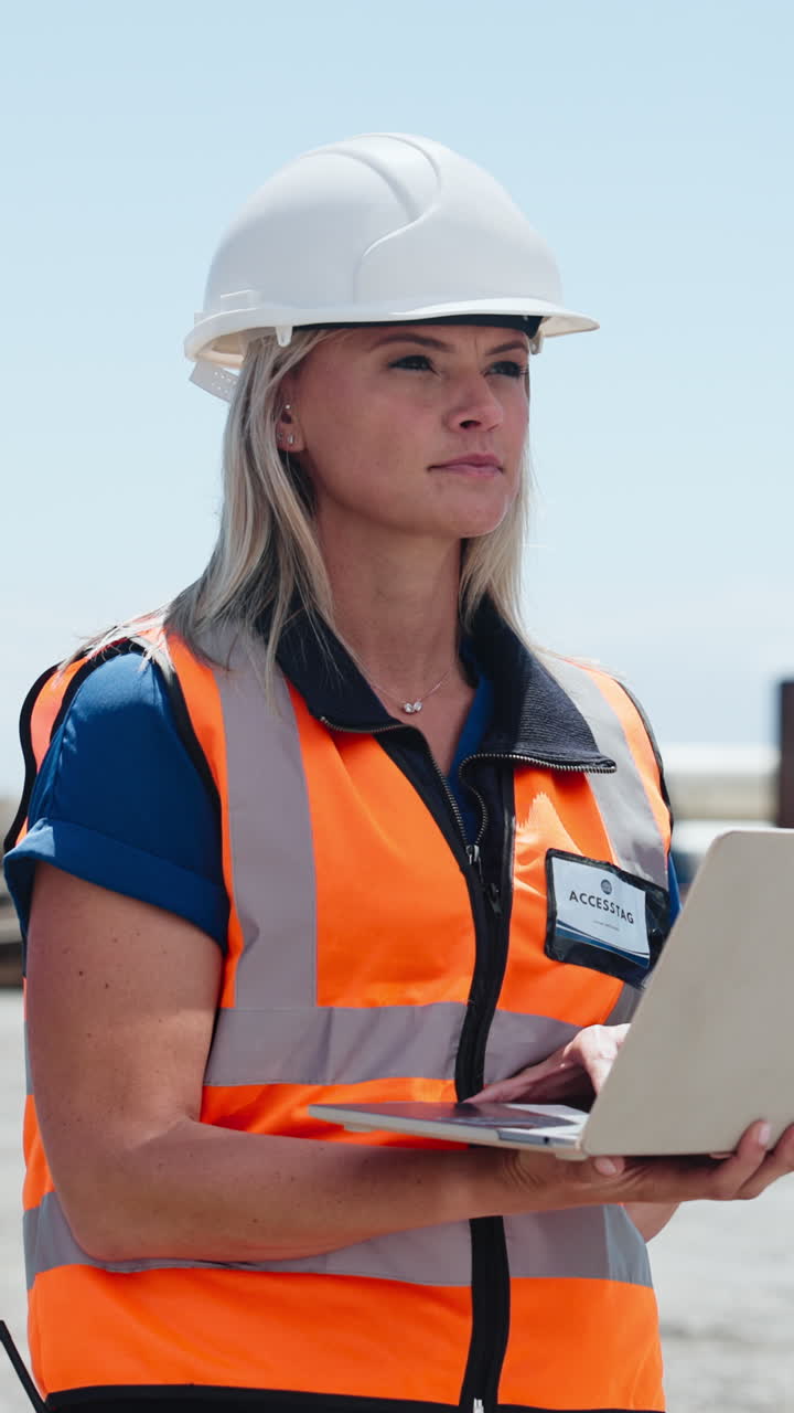 Female Engineer in Hard Hat and Safety Vest Working on Laptop Outdoors