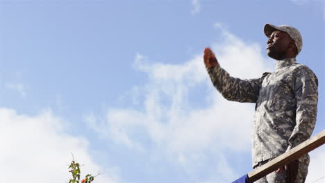 saluting, soldier in camouflage uniform standing outdoors against blue sky
