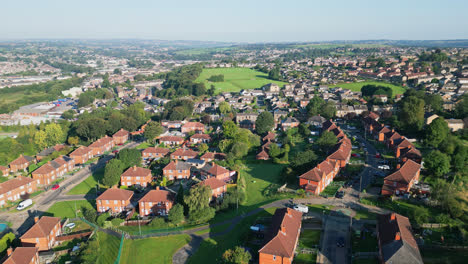 A-drone's-eye-view-of-Dewsbury-Moore-Council-estate,-UK,-displays-red-brick-homes-and-the-industrial-Yorkshire-landscape-on-a-sunny-summer-morning