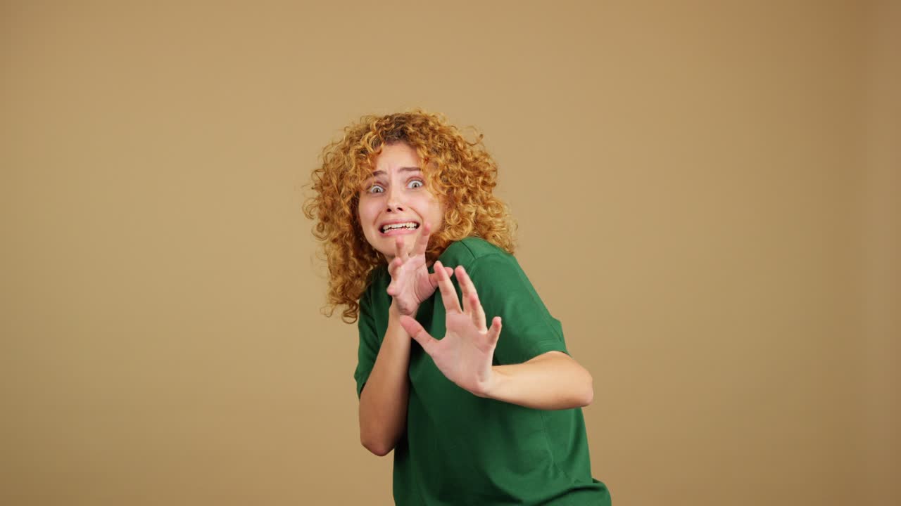 Young woman with curly hair looking scared and surprised