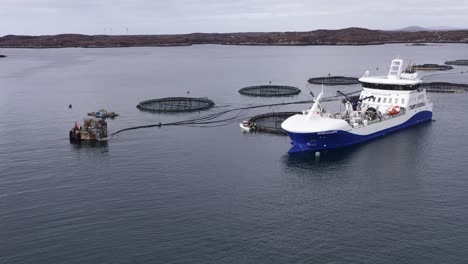 advancing shot of a well-boat maintaining a fish farming cage near uist