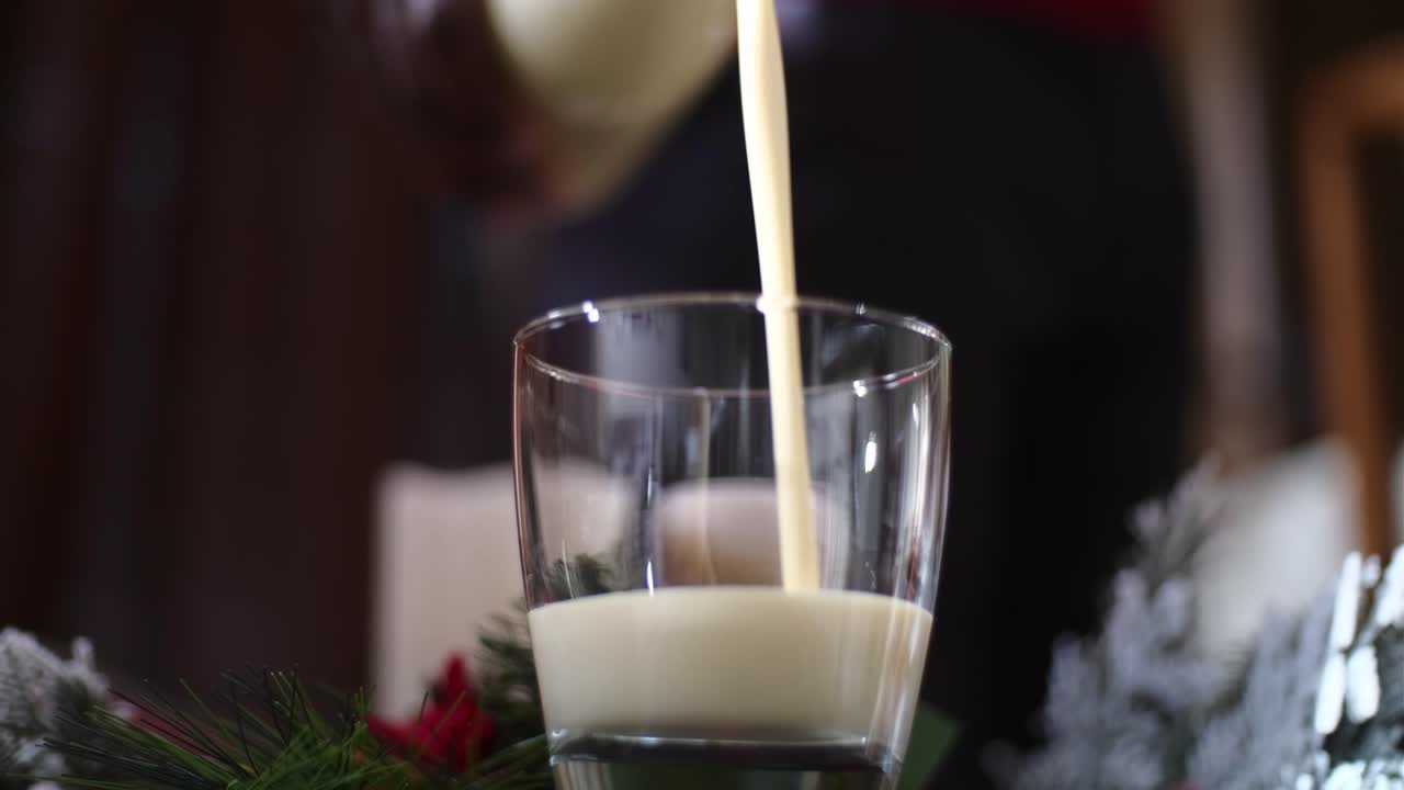 vista frontal de la mano de un hombre afroamericano sirviendo una bebida navideña tradicional ponche de huevo de navidad