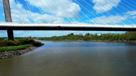 Drone-Volando-Bajo-El-Puente-Colgante-Thomas-Francis-Meagher-Sobre-El-Río-Suir-En-Waterford,-Irlanda,-En-Un-ángulo-único-Por-La-Mañana-Soleada