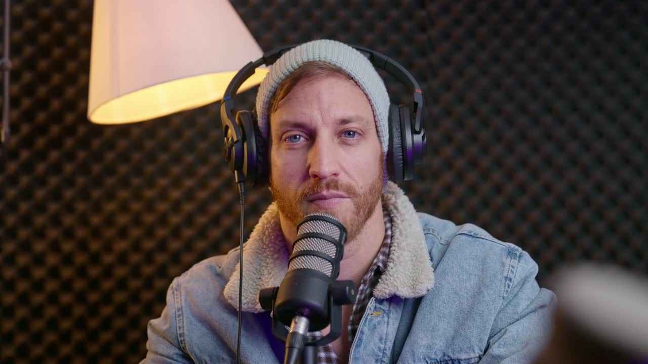 podcaster asintiendo con la cabeza y sonriendo mientras escucha a un invitado. expresión comprometida, entorno de estudio profesional, interacción dinámica de podcast, escucha activa, conversación, creación de contenido.